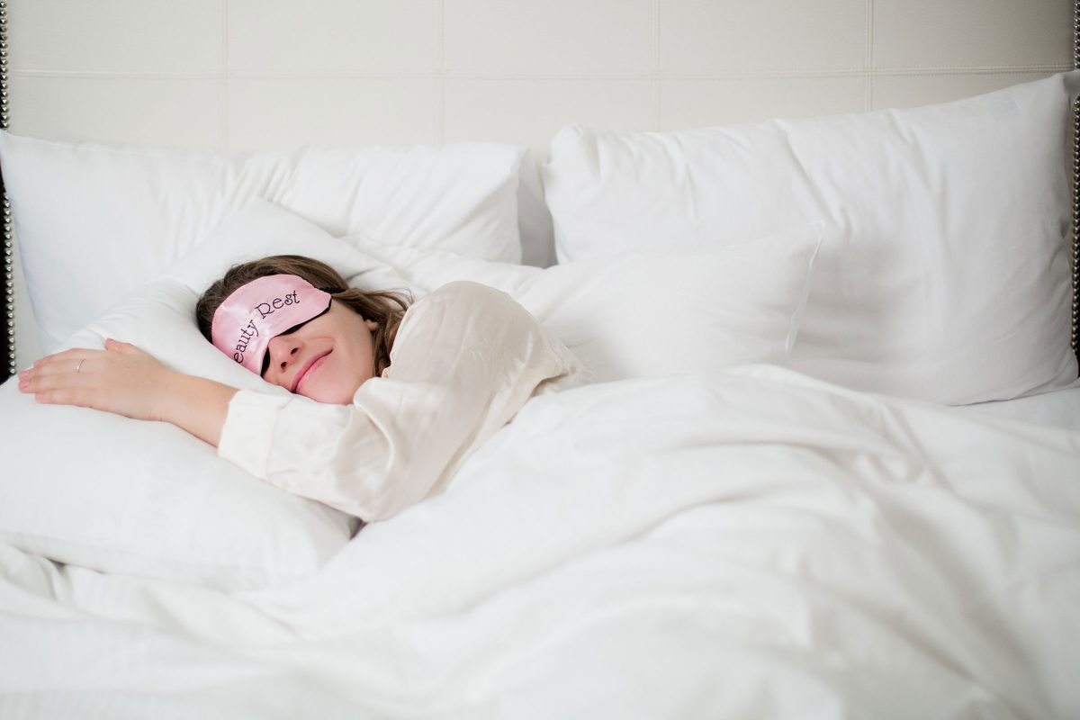 woman on white bed with eye mask